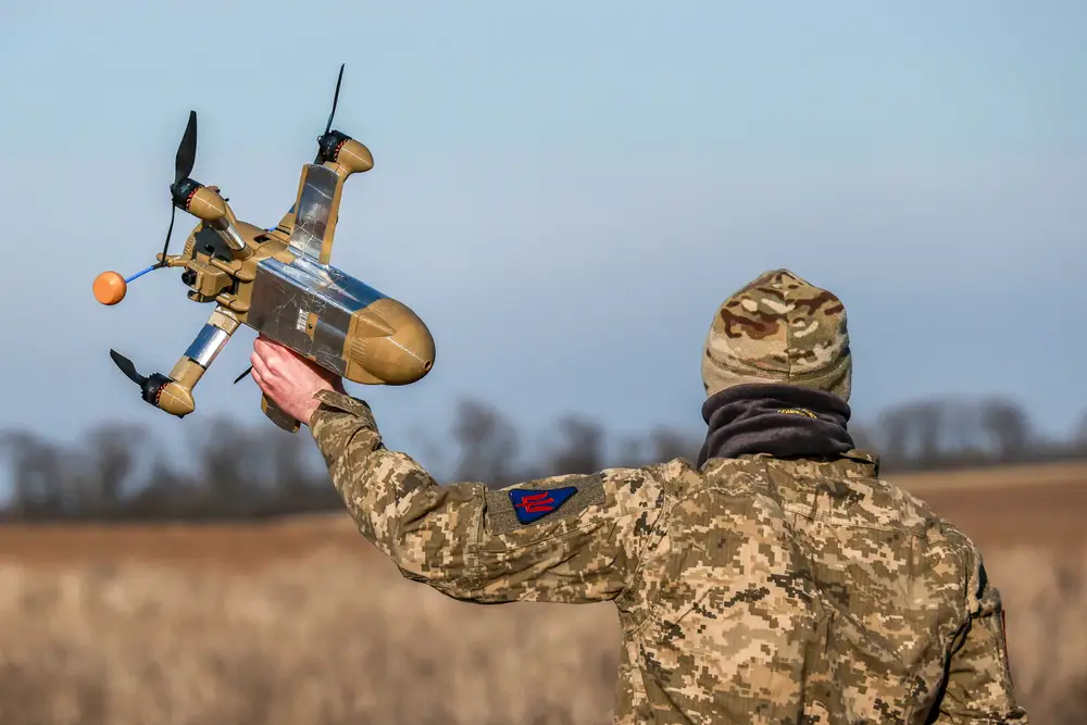 Soldier holding an interceptor drone in hand before deployment.