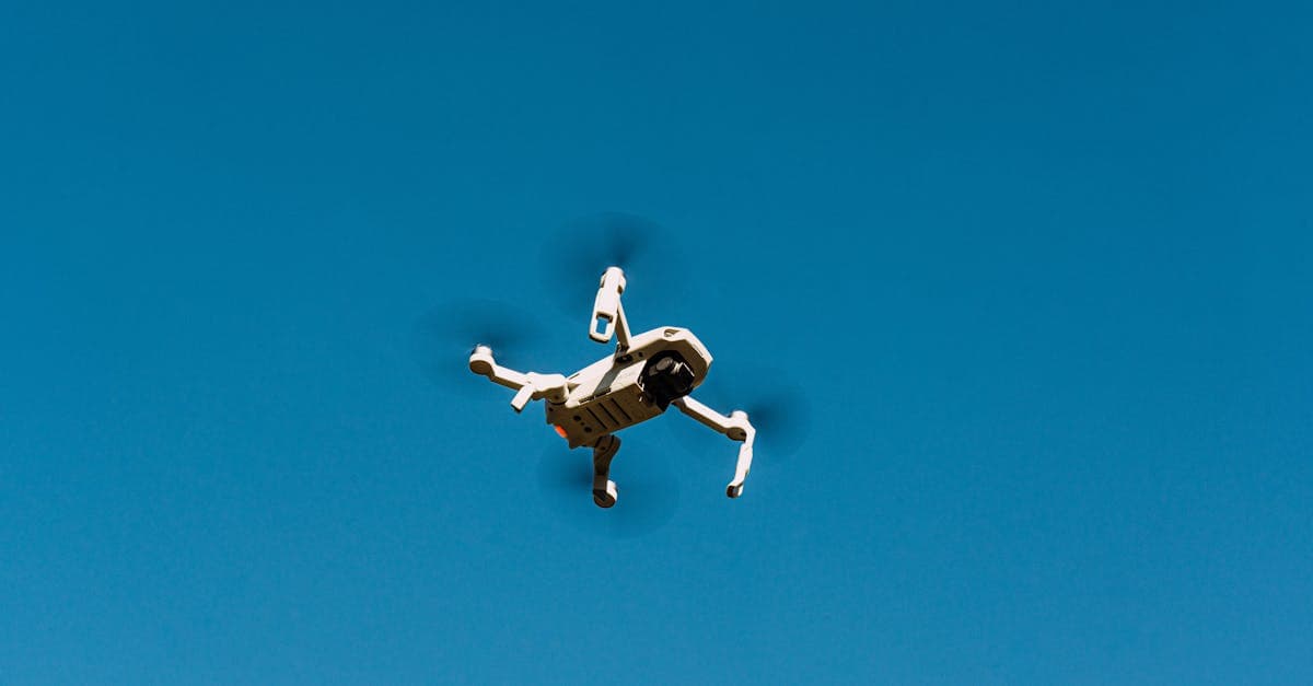 White drone flying in a clear blue sky for observation and aerial coverage.